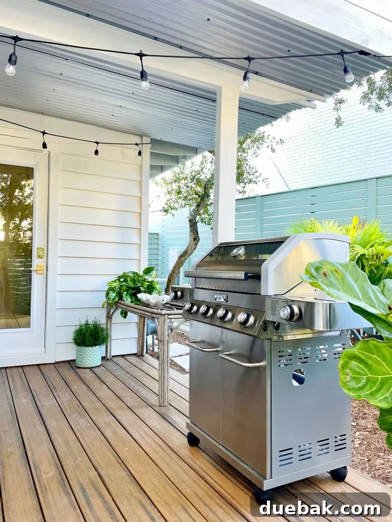 The sleek stainless steel grill gleaming on the covered kitchen porch, beautifully illuminated by string lights