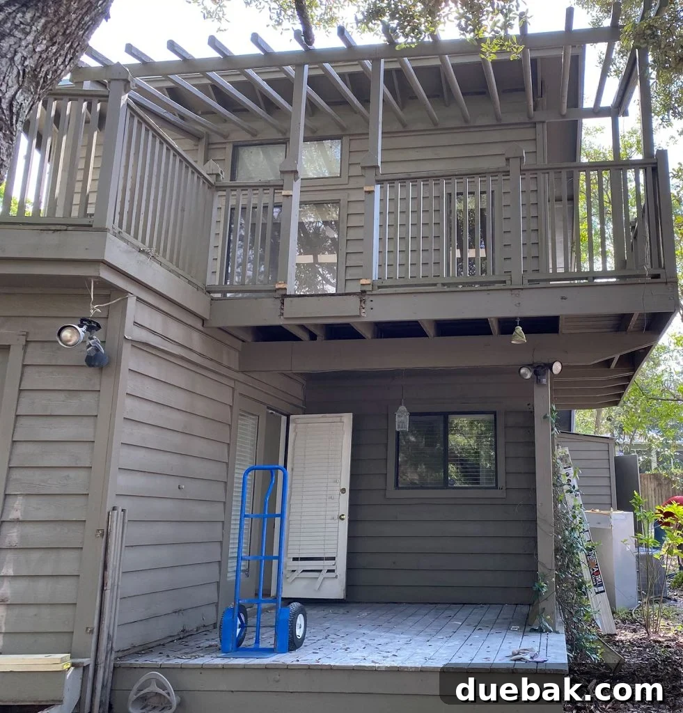 Before photo of a dated brown painted house with an unkempt side yard, showcasing the initial state of the porch