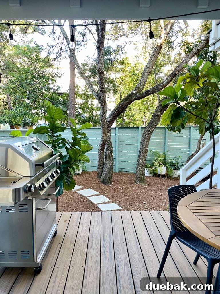 Vertical view from the covered patio, featuring a modern grill and outdoor table, all overlooking the lush greenery of the yard
