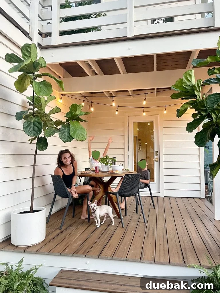 Family enjoying an outdoor meal on the covered porch, illuminated by string lights, with a happy chihuahua resting under the table