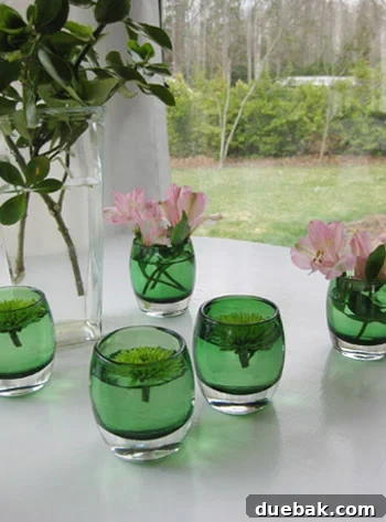Two clear glass votive holders featuring vibrant pink mums floating gracefully on water, positioned on a rustic wooden surface as a charming and affordable home decor accent.