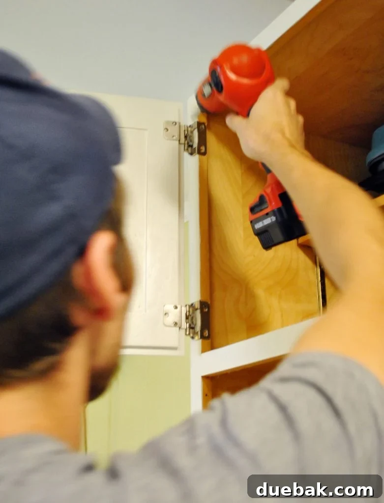 John reattaching cabinet door in painted kitchen