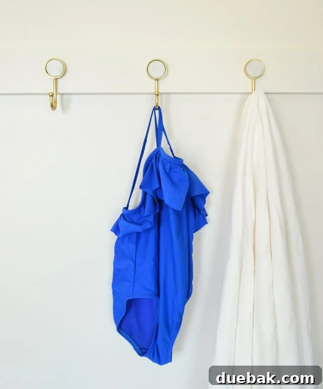 three gold hooks on diy rail with towel and bathing suit