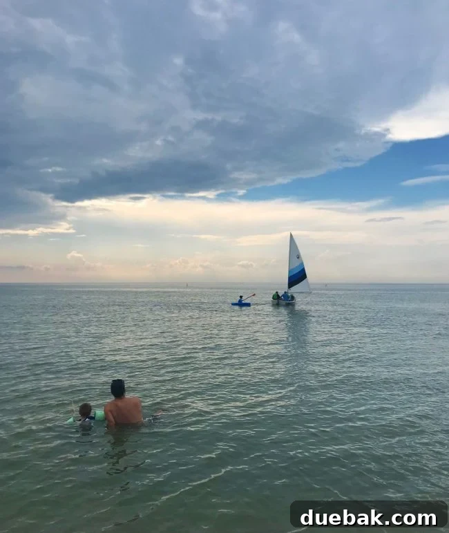 Cape Charles, VA: Your Guide to the Charming Beach Town 9 people sitting in water watching sailboat on cape charles beach