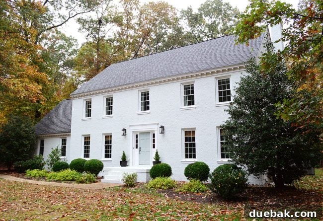 How We Transformed Our Brick House with White Paint 11 after photo of back of brick house painted moderne white in fall foliage