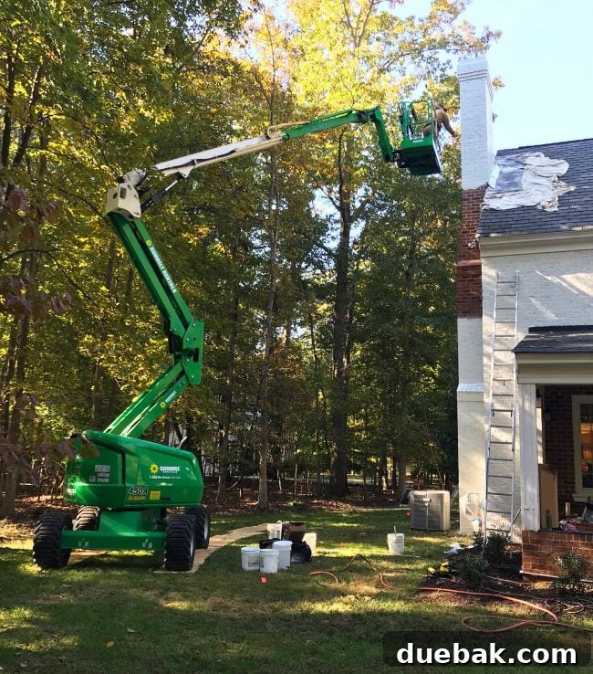 How We Transformed Our Brick House with White Paint 16 large lift crane raised to paint chimney of brick house