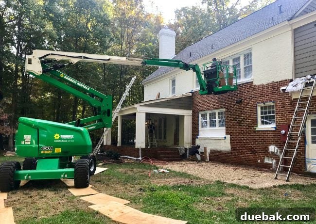 How We Transformed Our Brick House with White Paint 18 large crane lift used to paint the back of a brick house white