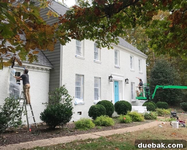 How We Transformed Our Brick House with White Paint 19 painters applying second coat of romabio biodomus paint to brick house