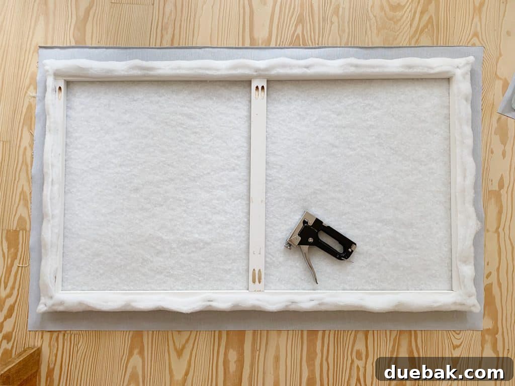 DIY Headboard Ideas: Simple Projects for a Stylish Bedroom 11 Batting covered wood frame laid on floor atop fabric prior to stapling