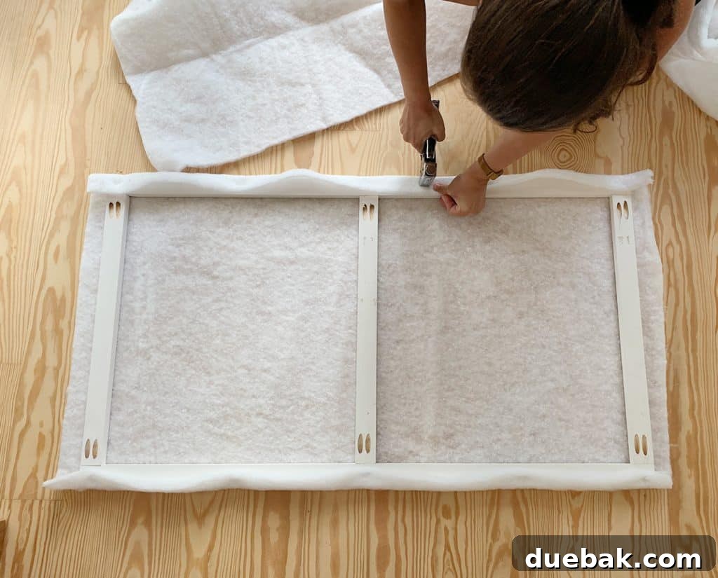DIY Headboard Ideas: Simple Projects for a Stylish Bedroom 8 Sherry stapling fabric batting around wood frame for DIY upholstered headboard