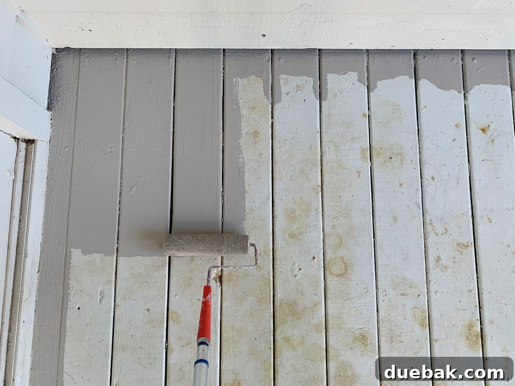 How to Paint a Porch Floor: Step-by-Step Guide for Lasting Results 6 Roller applying gray porch paint to stained white porch floor