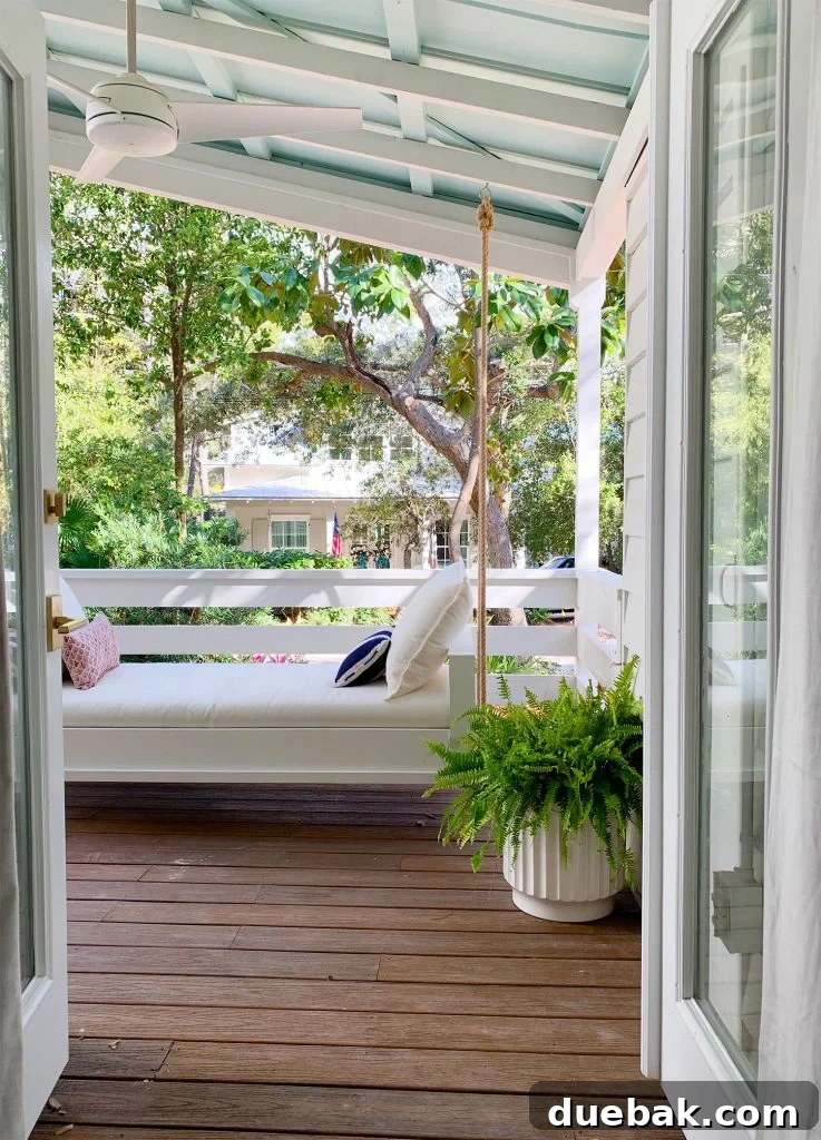 View Of White Hanging Daybed Swing Under Covered Porch Through Open French Doors
